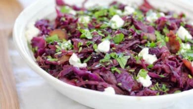 braised red cabbage topped with goat cheese and parsley in a white bowl