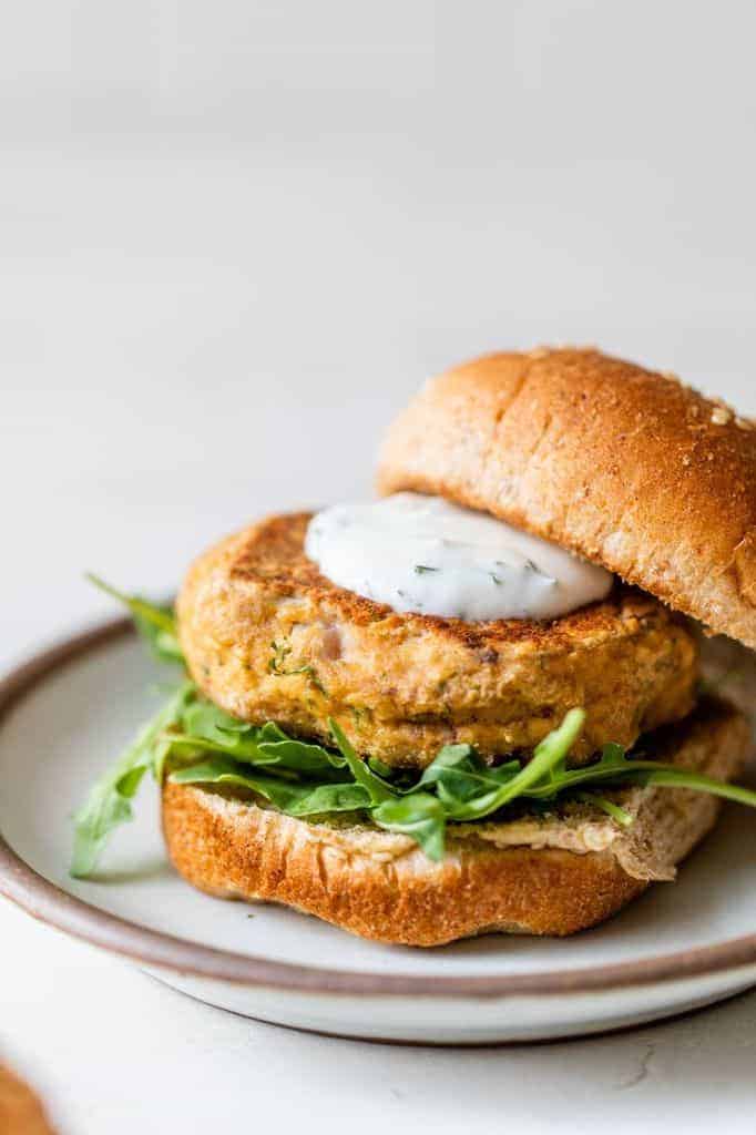 salmon burgers on a bun with arugula and dill sauce