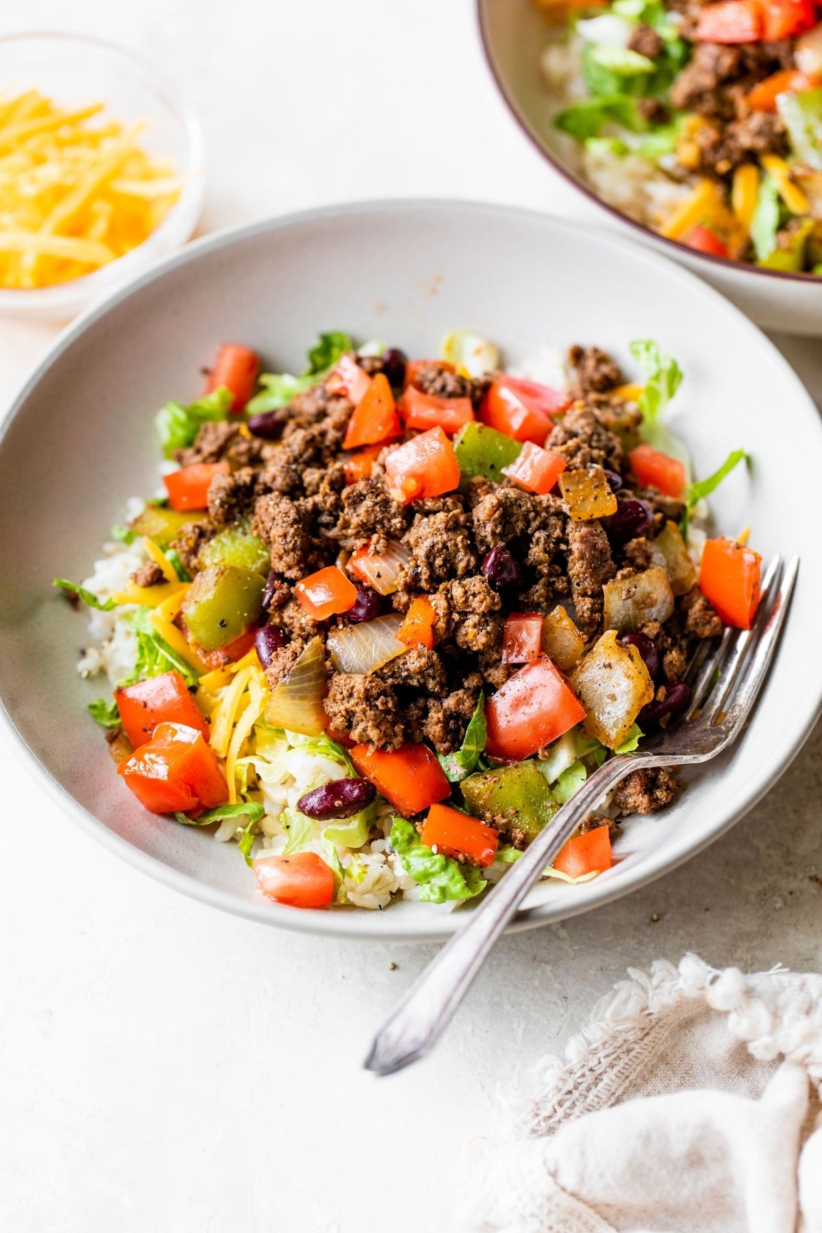 White bowl filled with lettuce, ground meat and tomatoes.