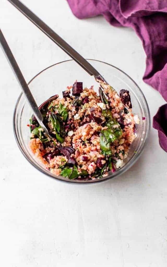 serving beet quinoa salad with tongs