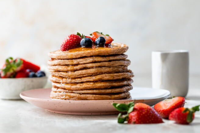 a stack of cottage cheese pancakes topped with fresh berries and maple syrup