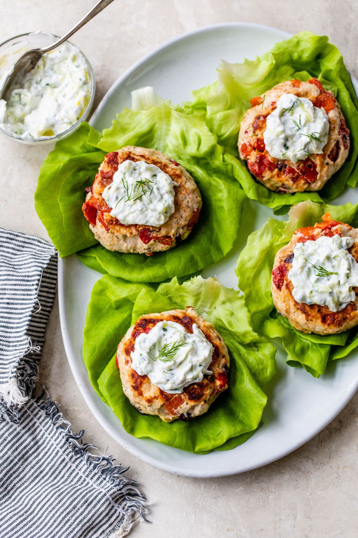 Burger patties on lettuce leaves topped with sauce.