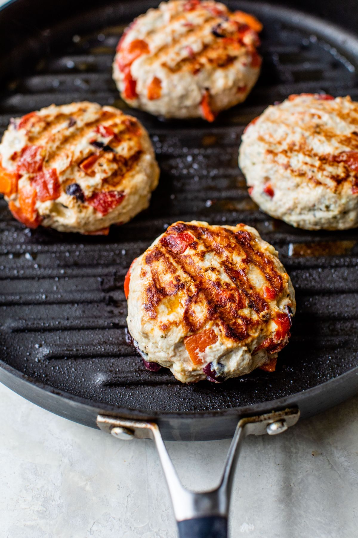 Turkey burgers cooking on a grill pan.