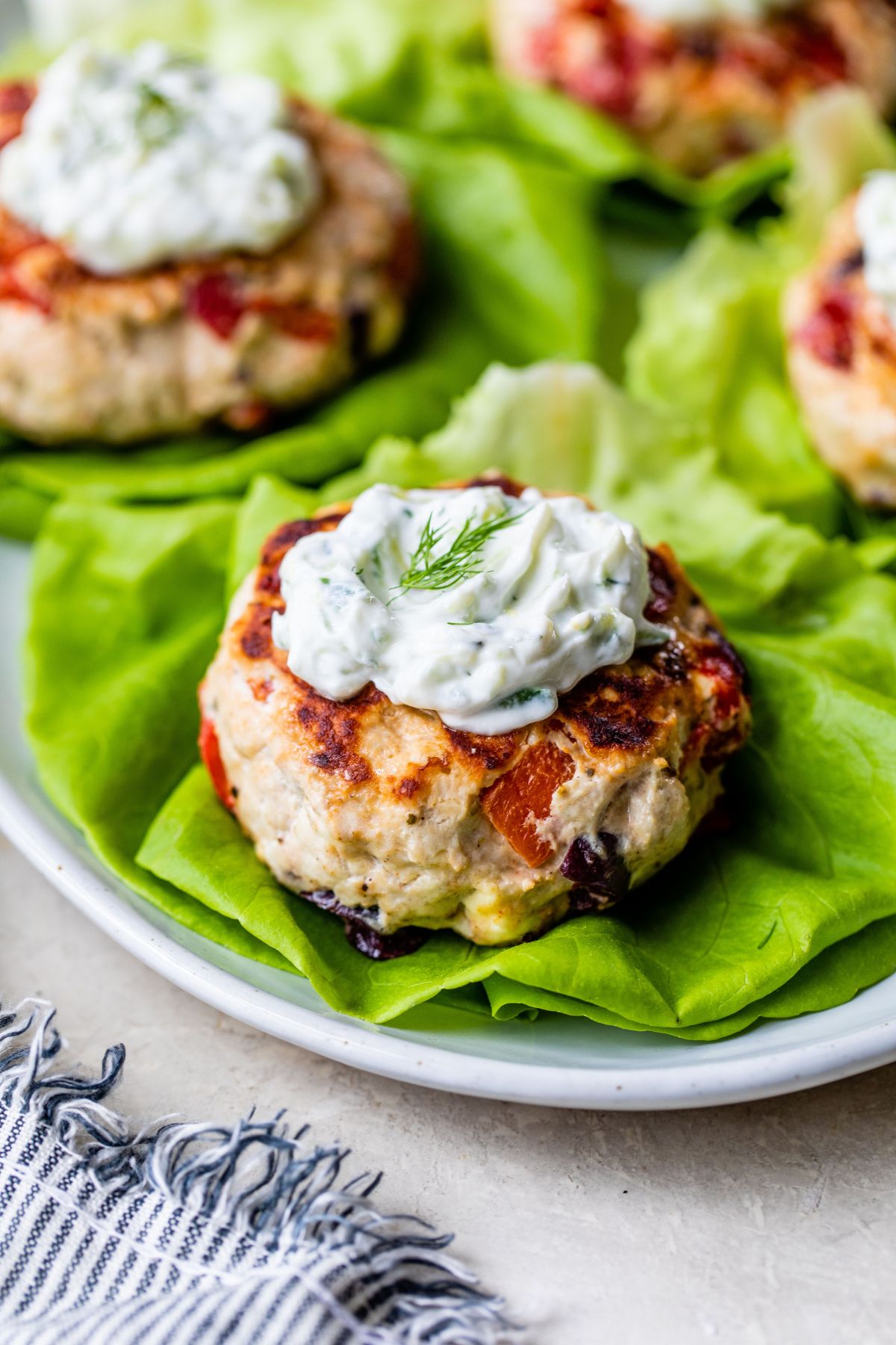 Greek Turkey Burgers served on lettuce and topped with Tzatziki sauce.
