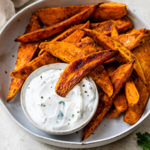 baked sweet potato wedges with garlic dip in a bowl