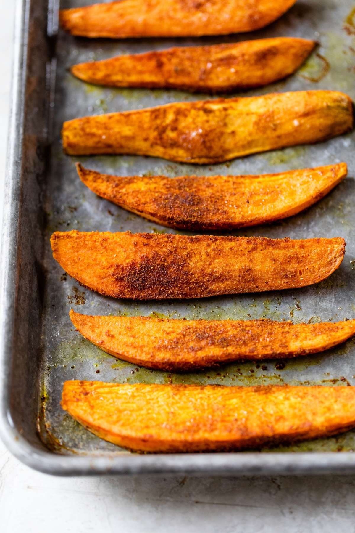 Roasted sweet potato wedges on a pan.