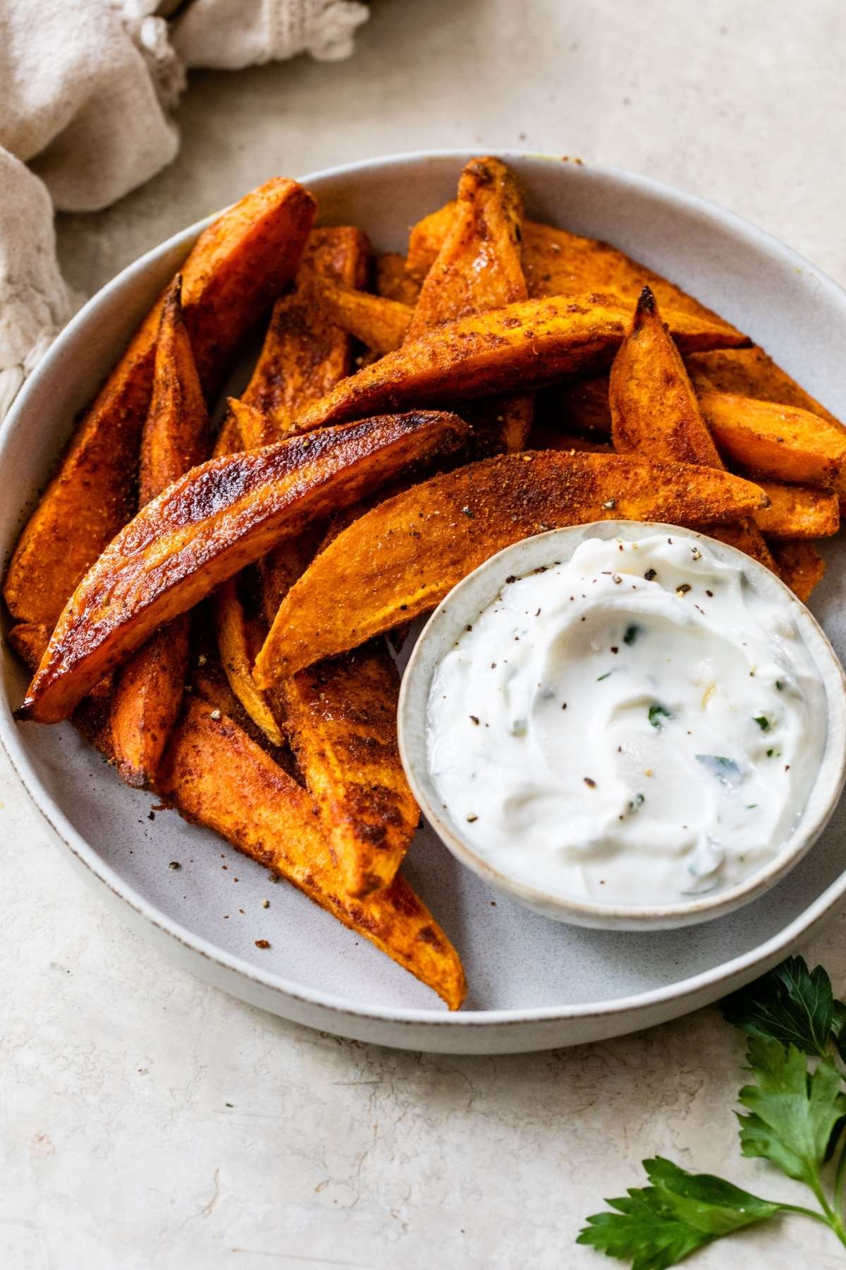 Roasted sweet potatoes served with dipping sauce on a white plate.