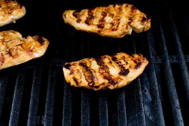 Chicken breasts on the grill with char marks.