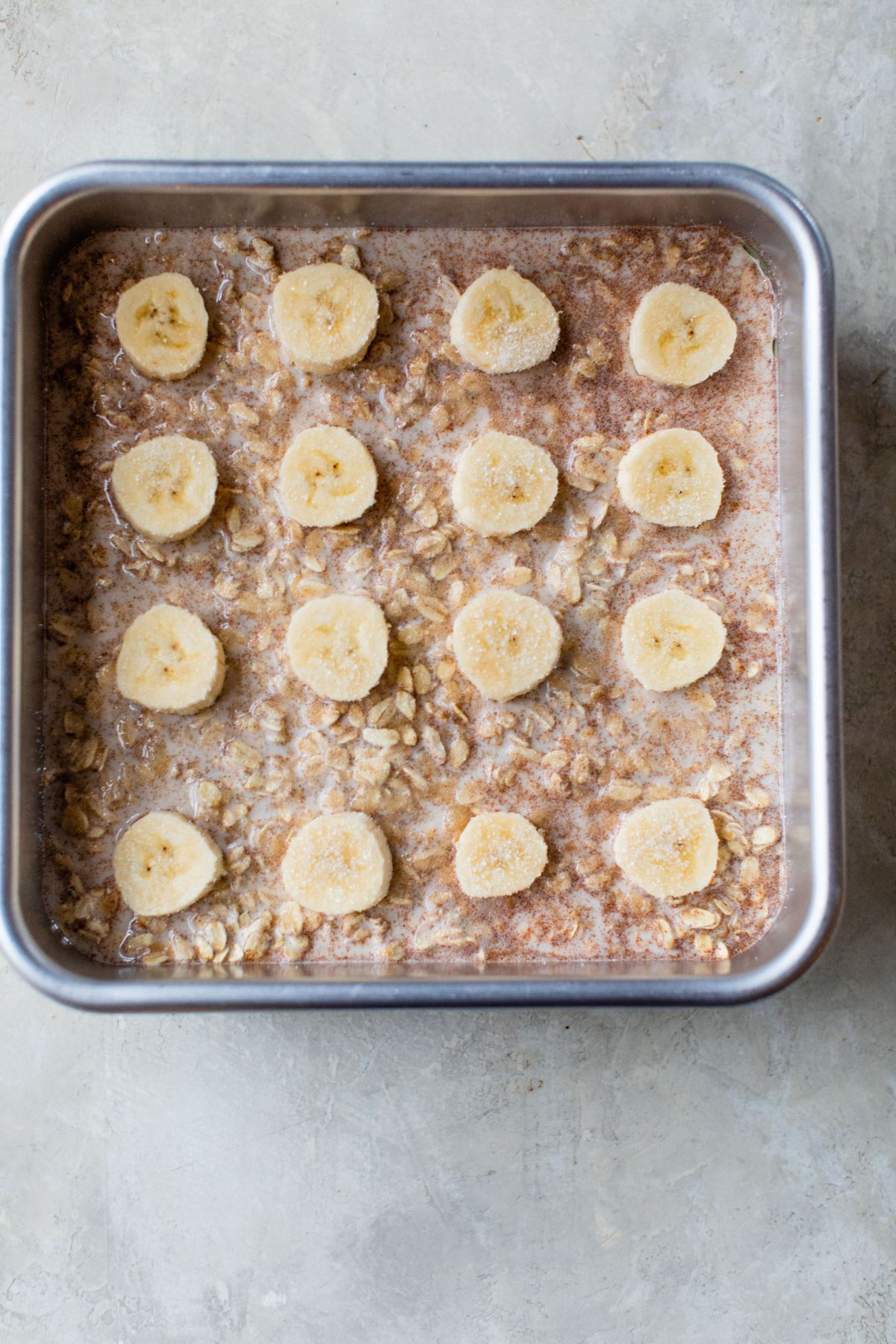 Oatmeal batter topped with sliced banana in pan.