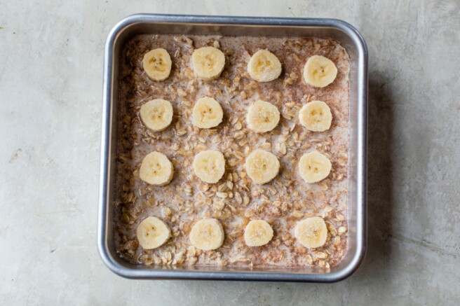 Oatmeal batter topped with sliced banana in pan.