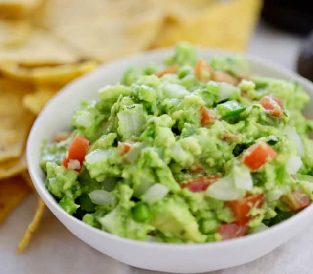 bright fresh bowl of guacamole with corn chips on the side