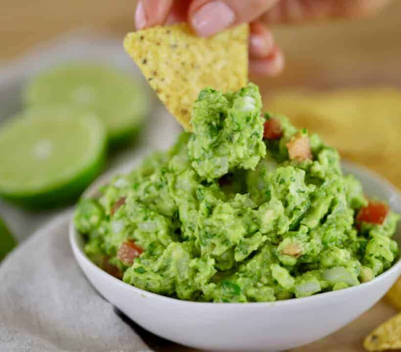 corn chip dipping into a bowl of fresh guacamole