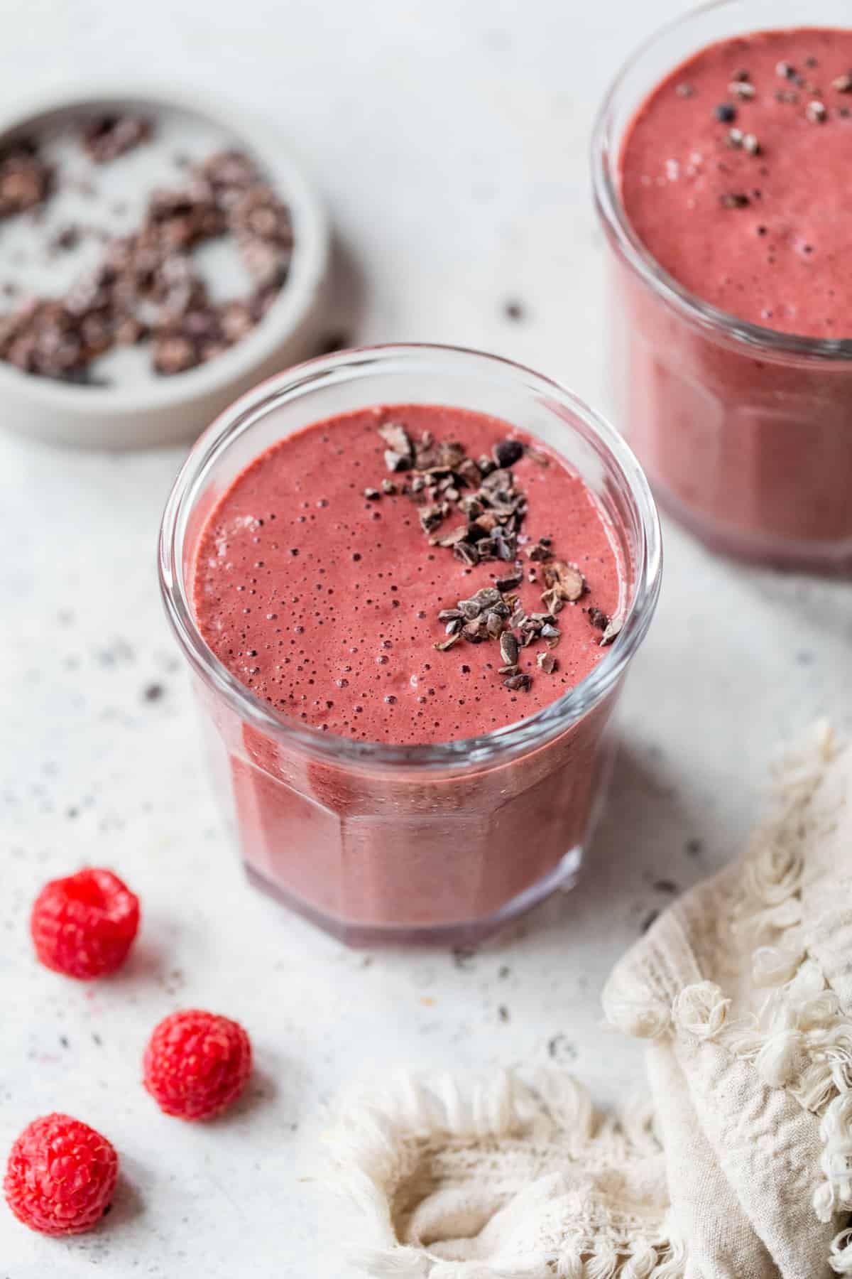 chocolate raspberry protein smoothie in glasses topped with cacao nibs