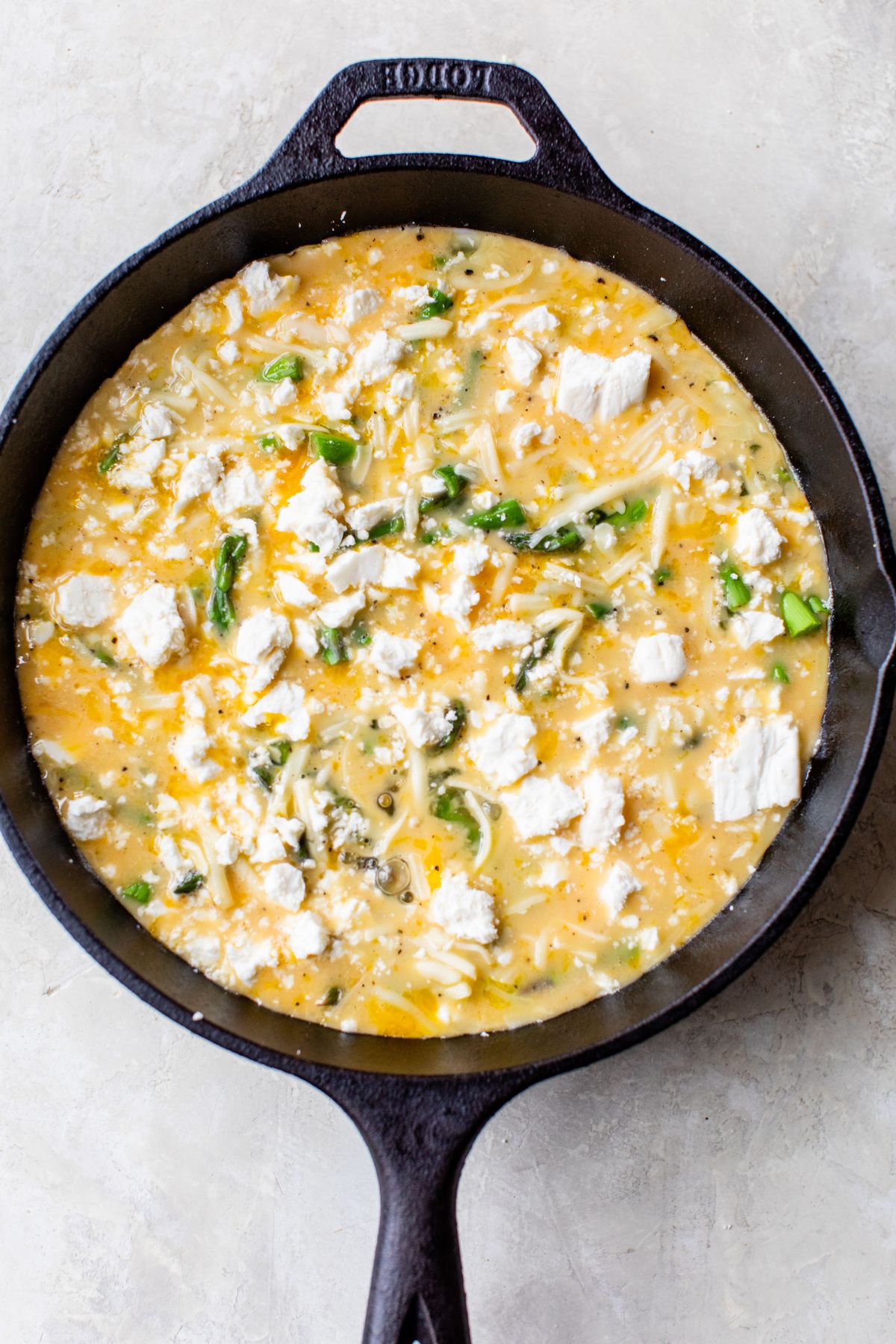 Sprinkling cheese over eggs cooking in a pan.