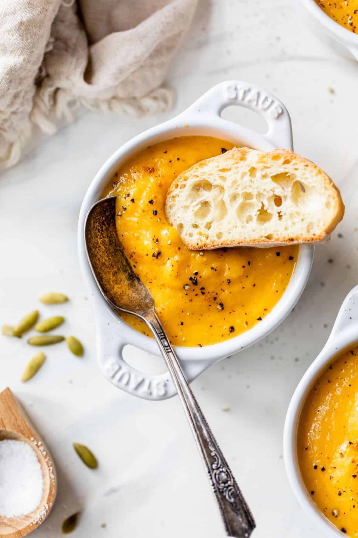 butternut squash apple soup served with a slice of crusty bread