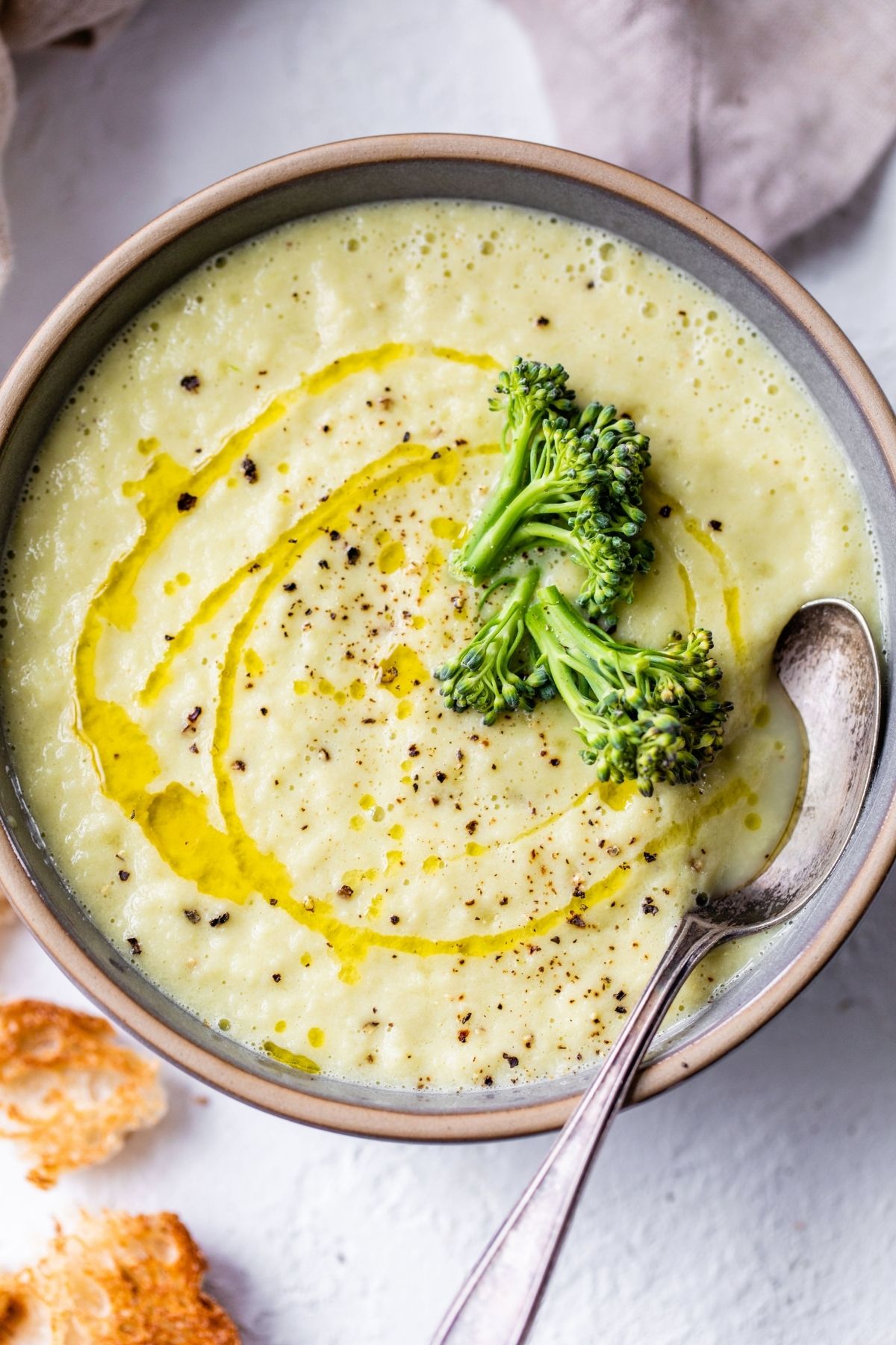 Broccoli stem soup in a bowl with a spoon and topped with a broccoli floret.