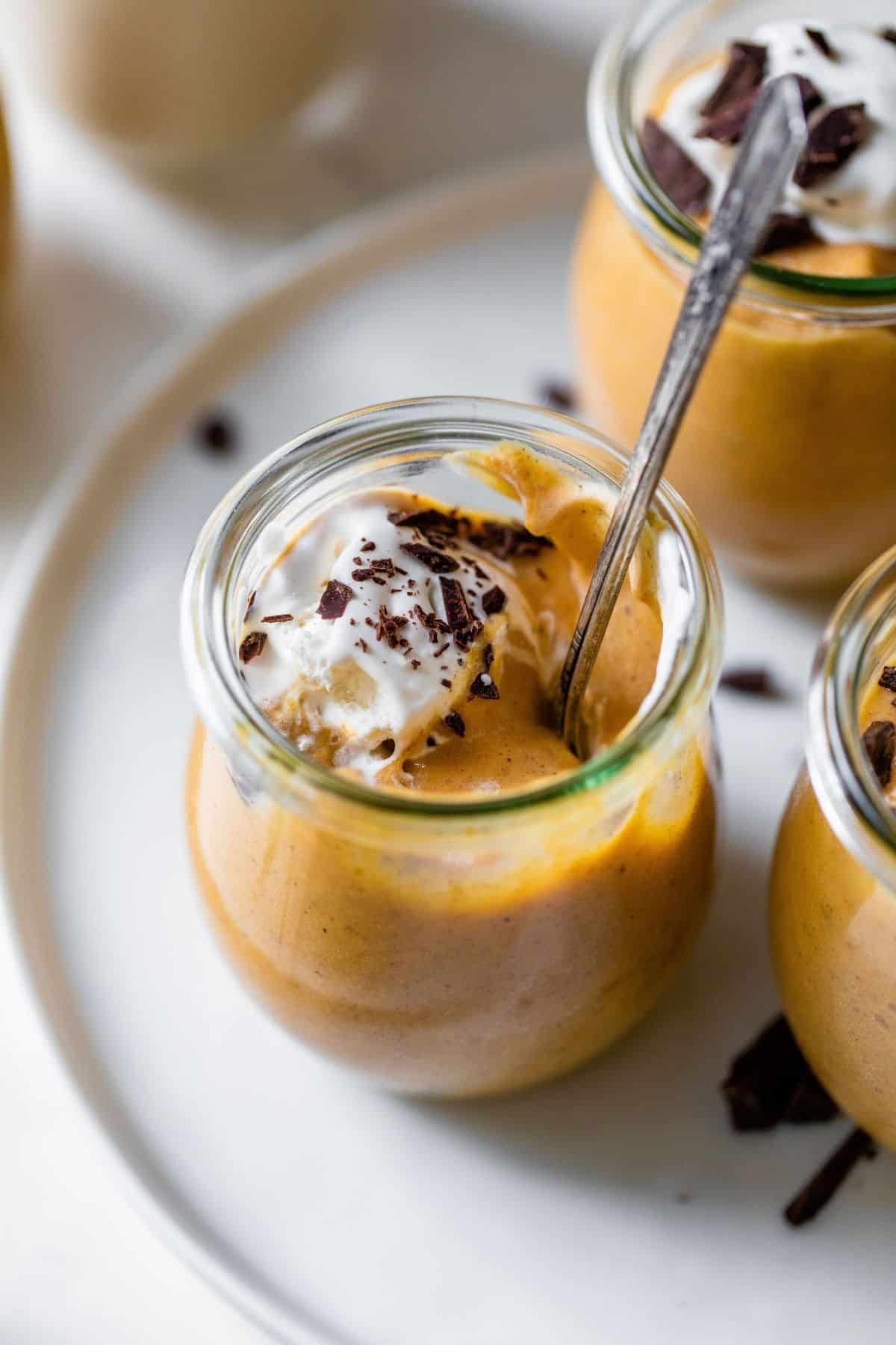 pumpkin mousse served in a small glass jar with a spoon