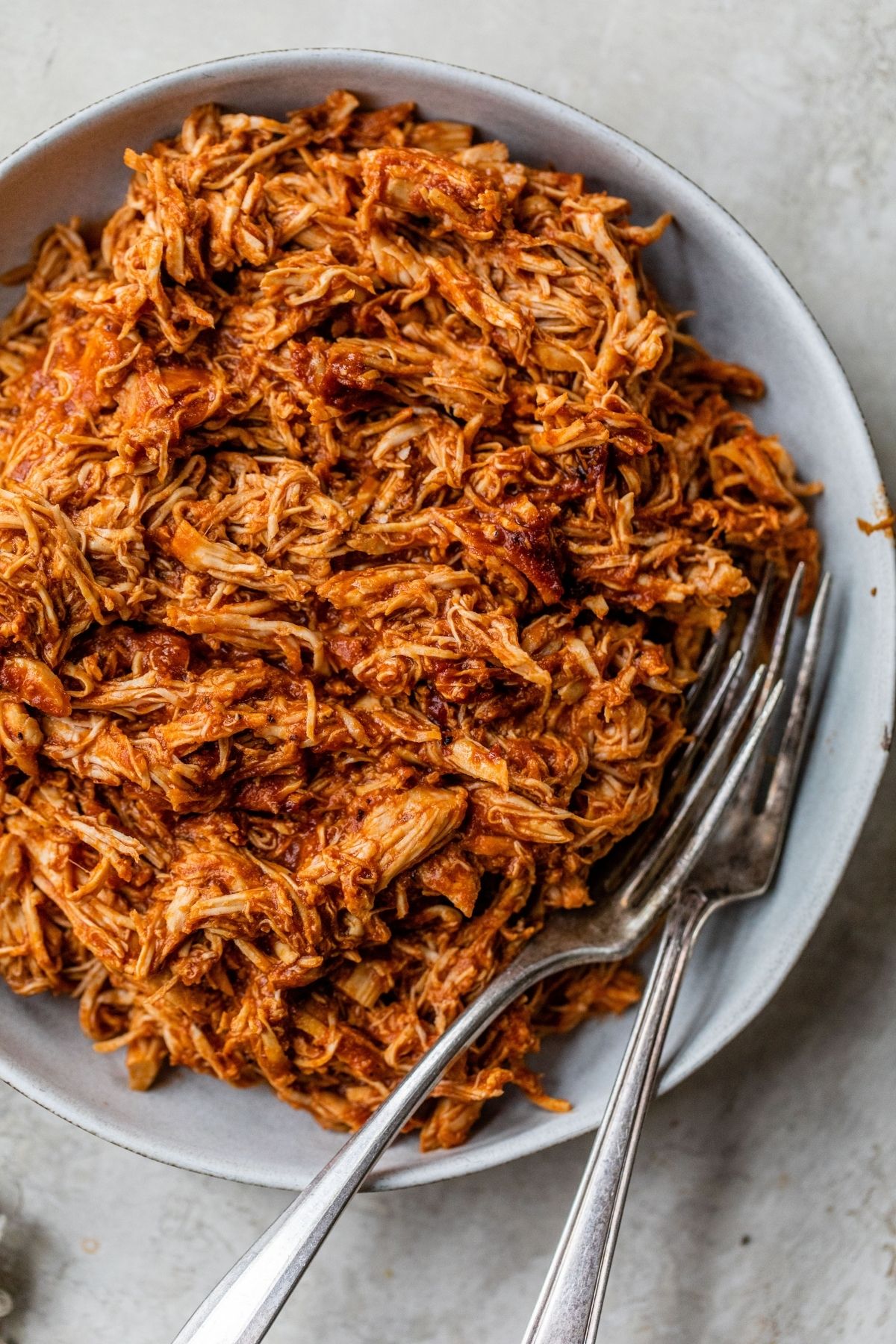 Shredded BBQ chicken on a plate with two forks.