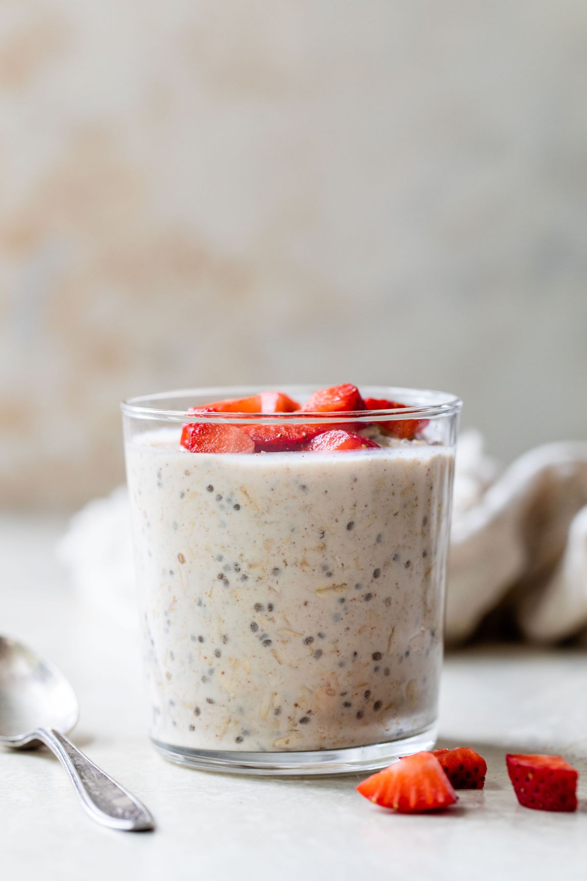 Overnight oats in a glass topped with fresh chopped strawberries.