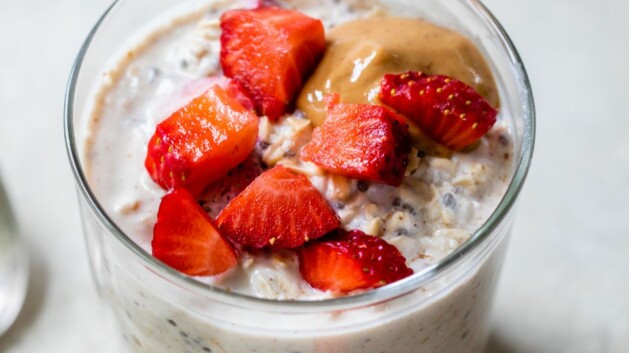 Glass jar with strawberry overnight oats topped with peanut butter.