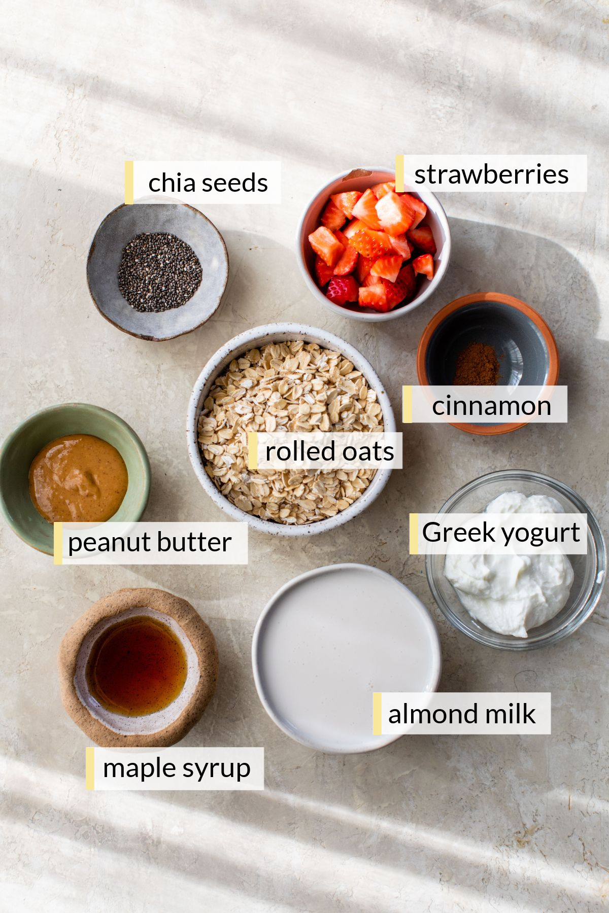 Ingredients for making strawberry overnight oats divided into small bowls.