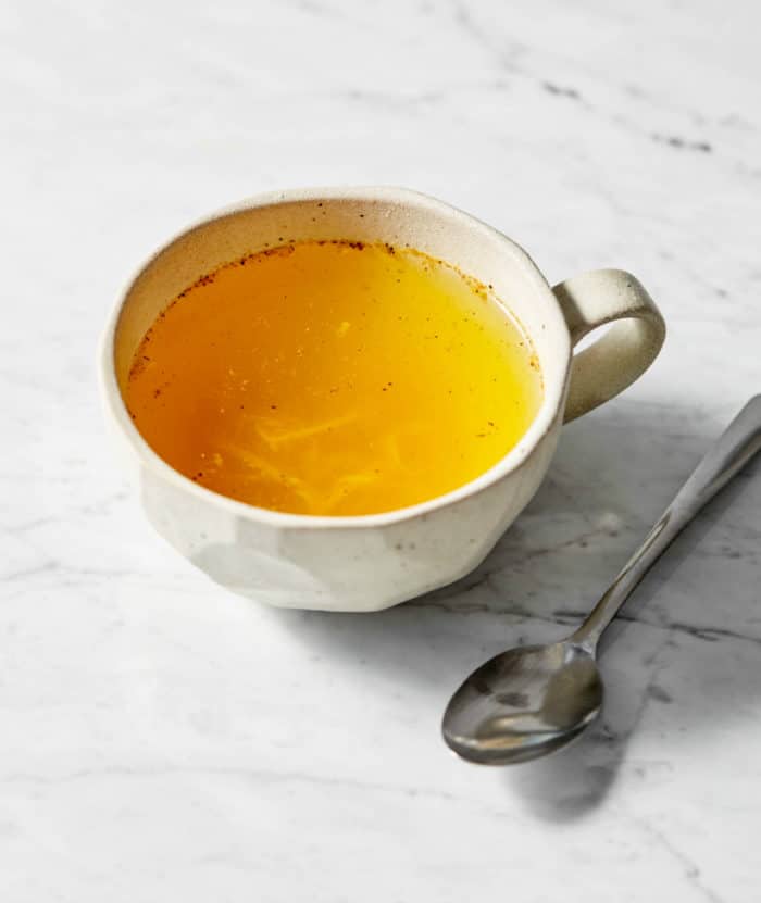 yellow drink in a mug near a spoon