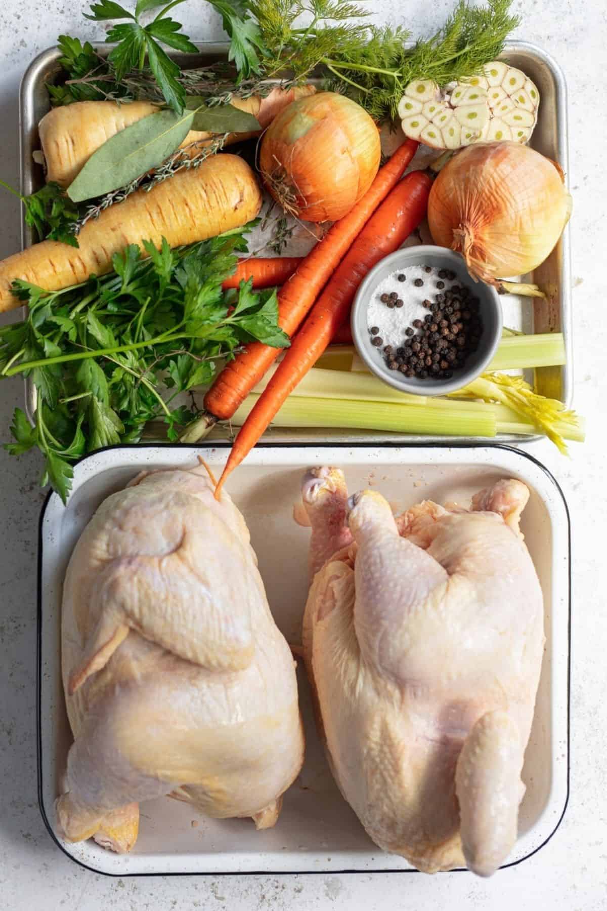 raw roasting chickens and veggies on a tray