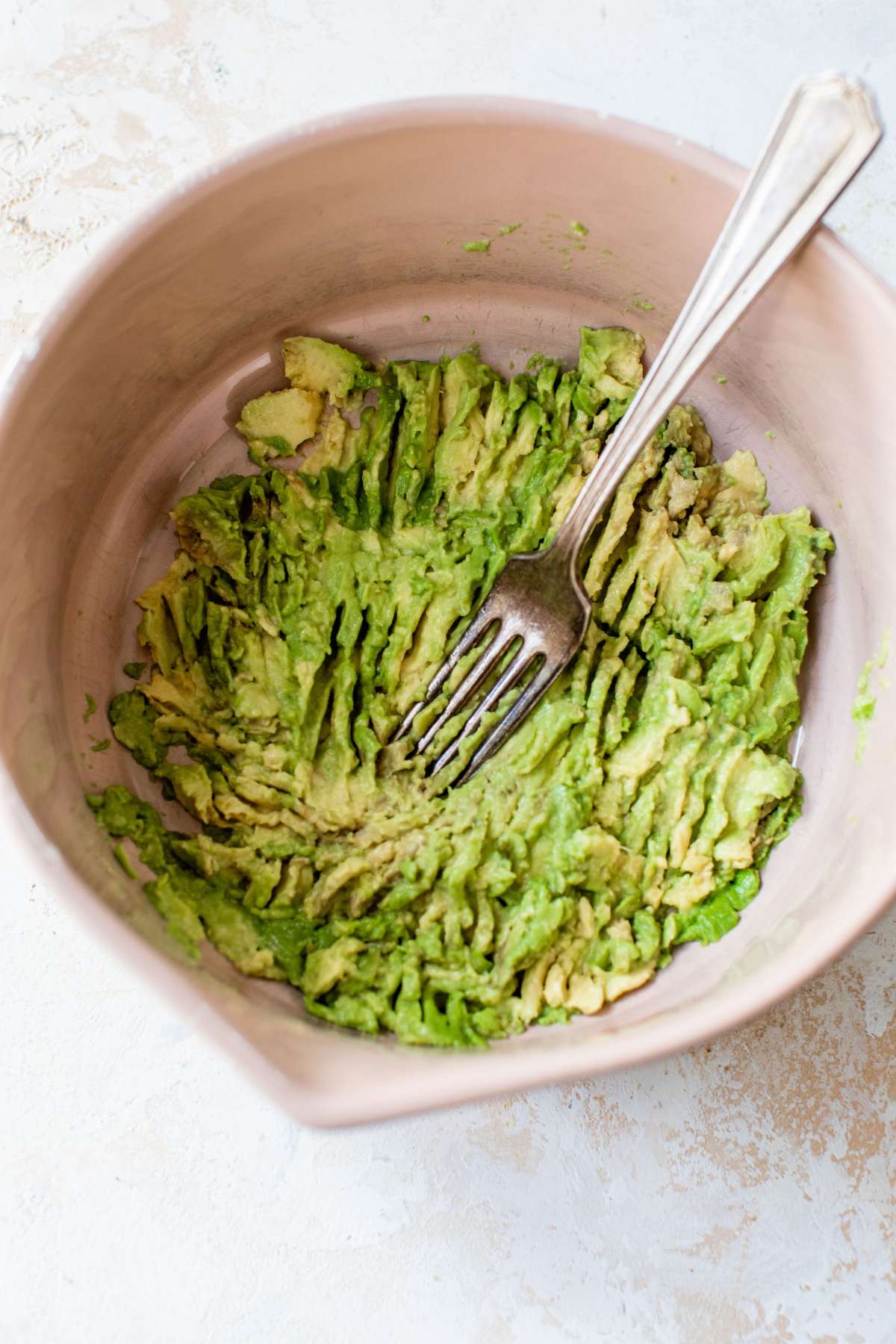 Mashing an avocado with a fork in a large. 