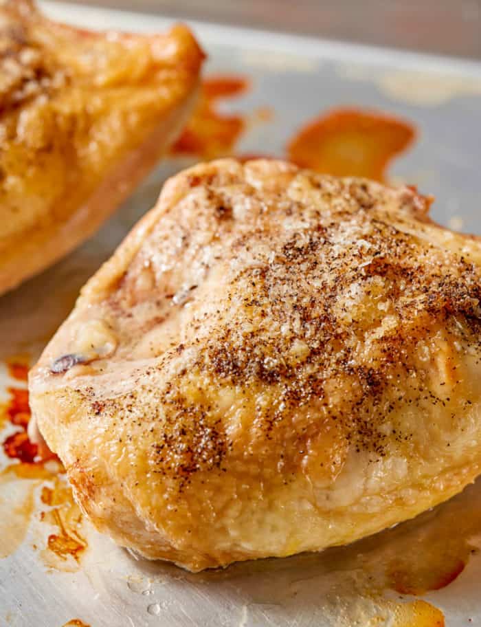 cooked bone-in chicken breast on a baking sheet pan