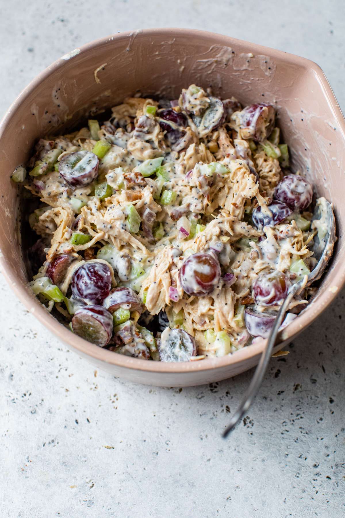 Stirring together chicken salad with Greek yogurt dressing in a large bowl.