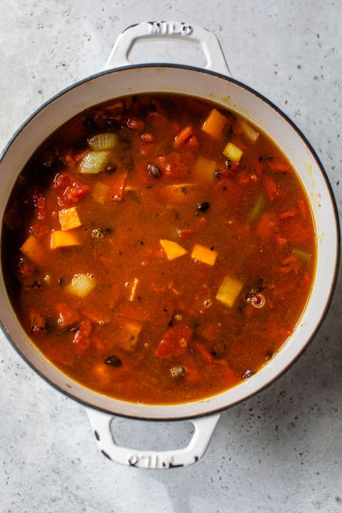 Cooking soup with tomatoes, sweet potato and black beans.