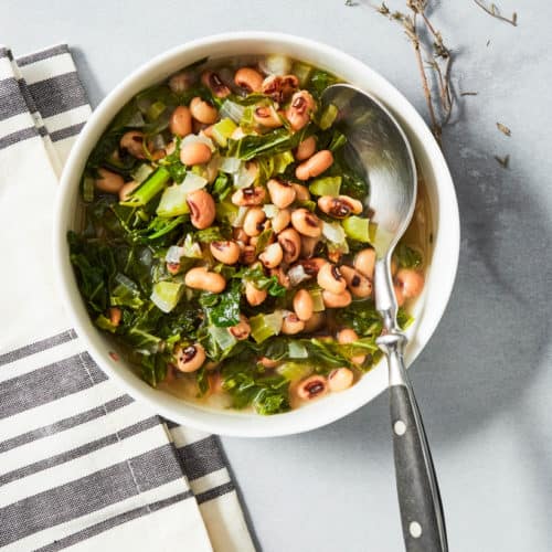 black eyed peas and collard greens served in a white bowl with a spoon