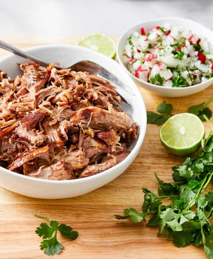 slow cooker pork in white bowl with lime and cilantro