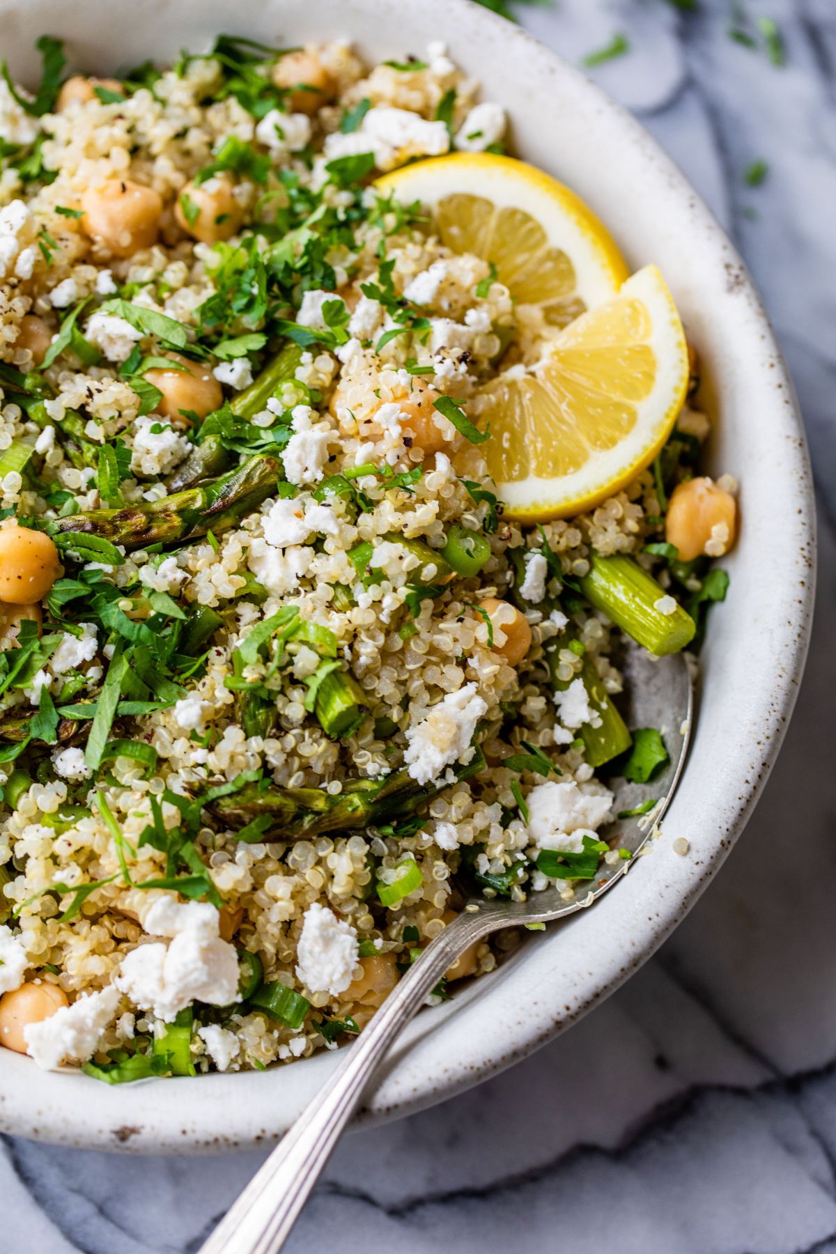 Quinoa Asparagus Salad topped with feta and served with lemon wedges.