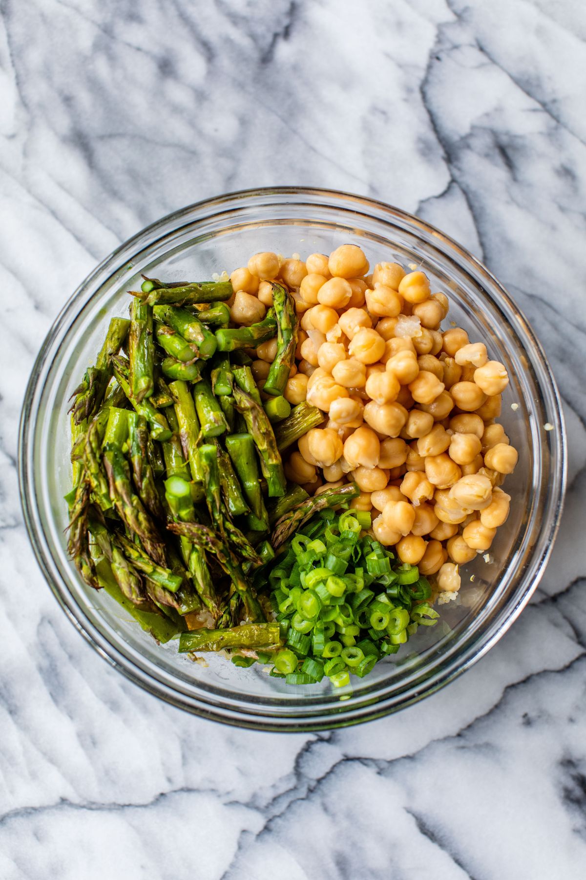 Adding chickpeas, roasted asparagus and sliced scallions to a large bowl.