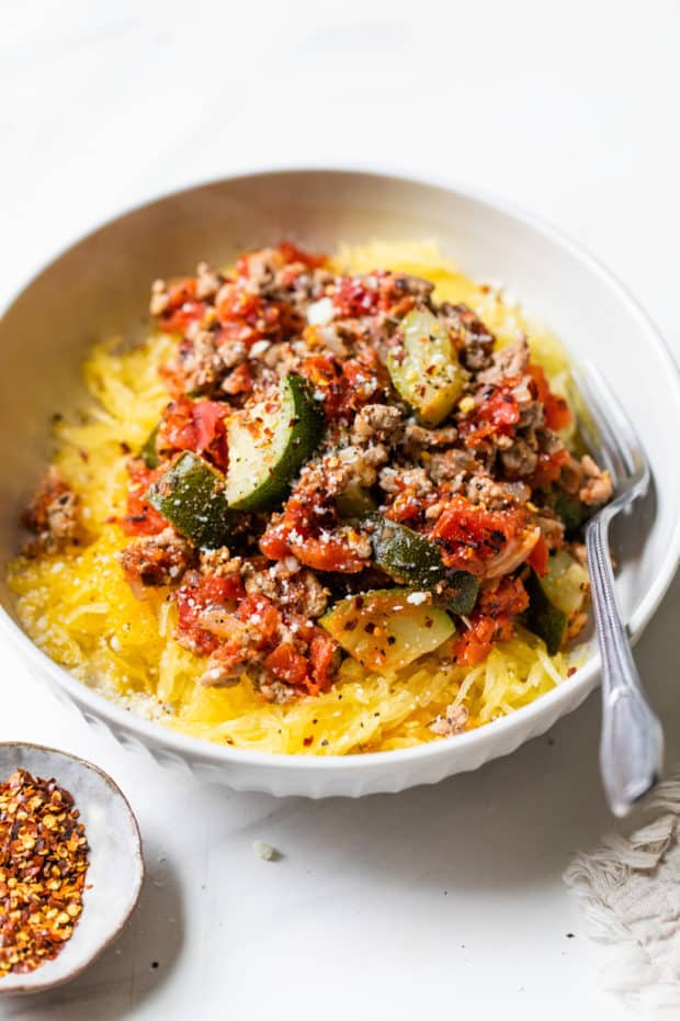 white bowl filled with spaghetti squash, ground turkey and zucchini with a fork