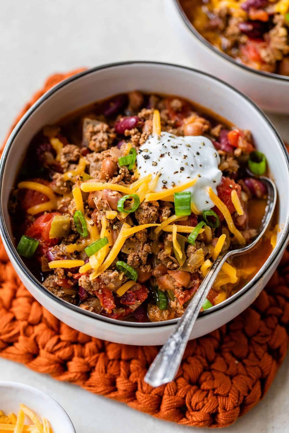 chili con carne topped with sour cream, shredded cheese and green onion 