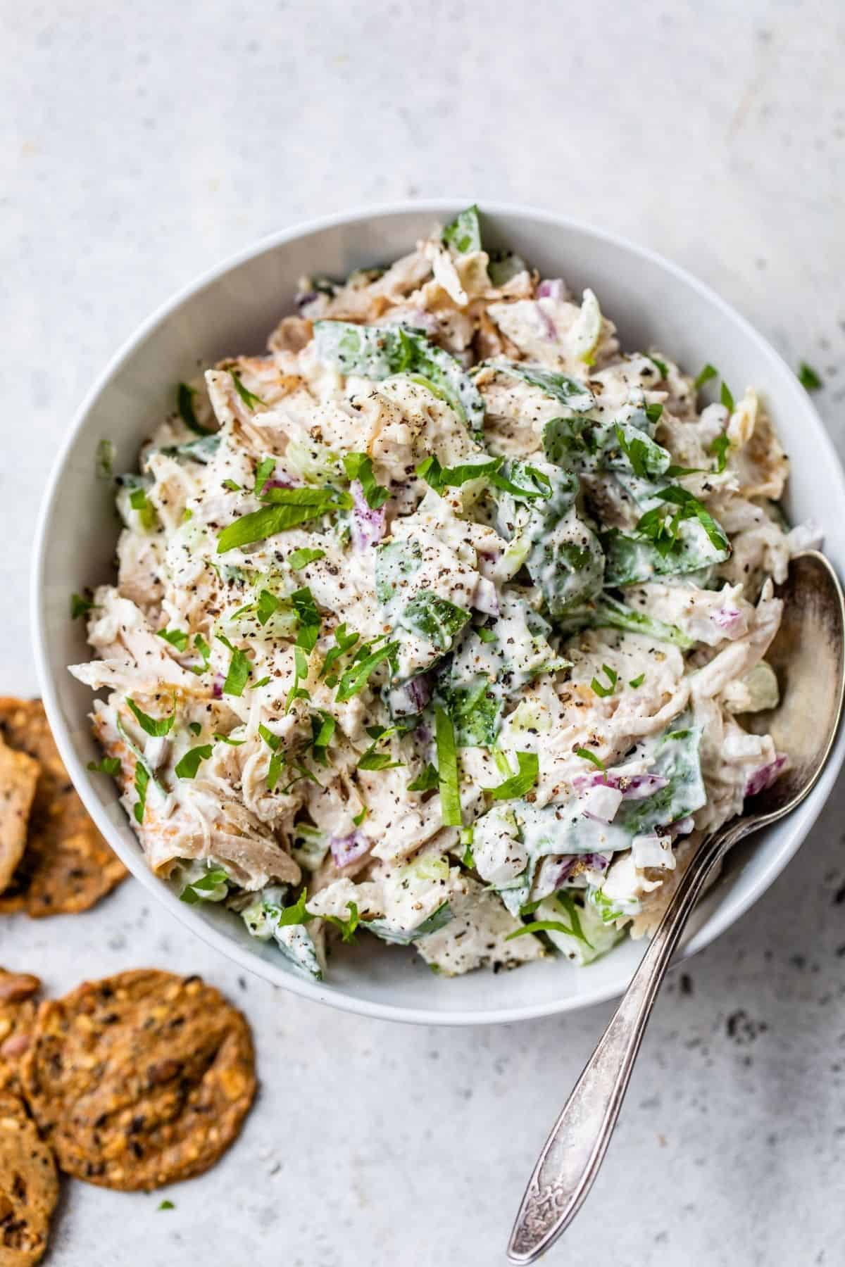 rotisserie chicken salad served in a white bowl with a spoon