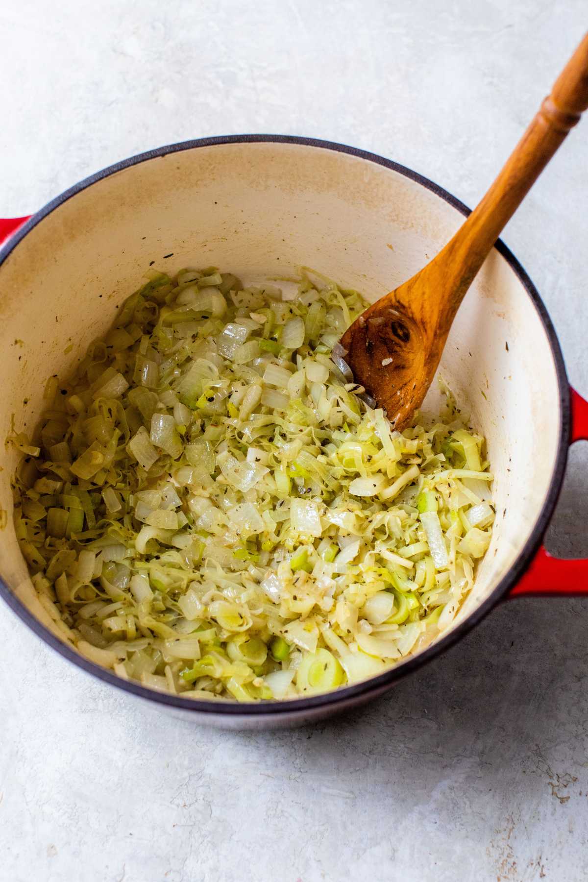 Stirring onions and leeks sautéing in a large pot.