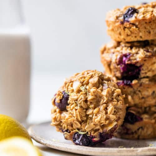 blueberry oatmeal muffins stacked on a plate and served with milk
