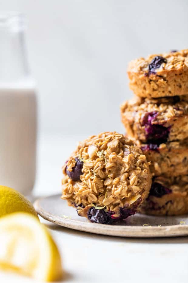 blueberry oatmeal muffins stacked on a plate and served with milk