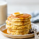 Thick pancakes stacked and topped with butter and maple syrup.