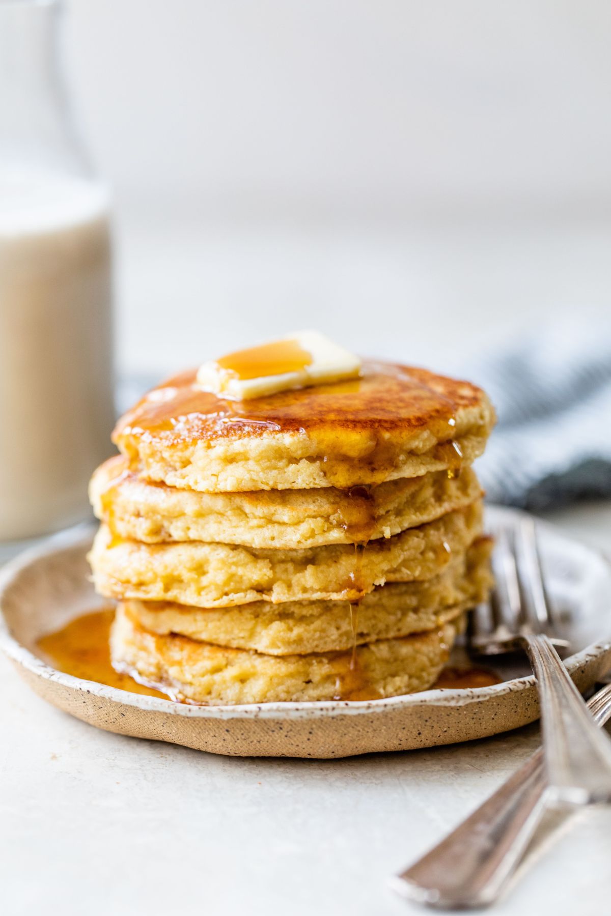 Thick pancakes stacked and topped with butter and maple syrup.
