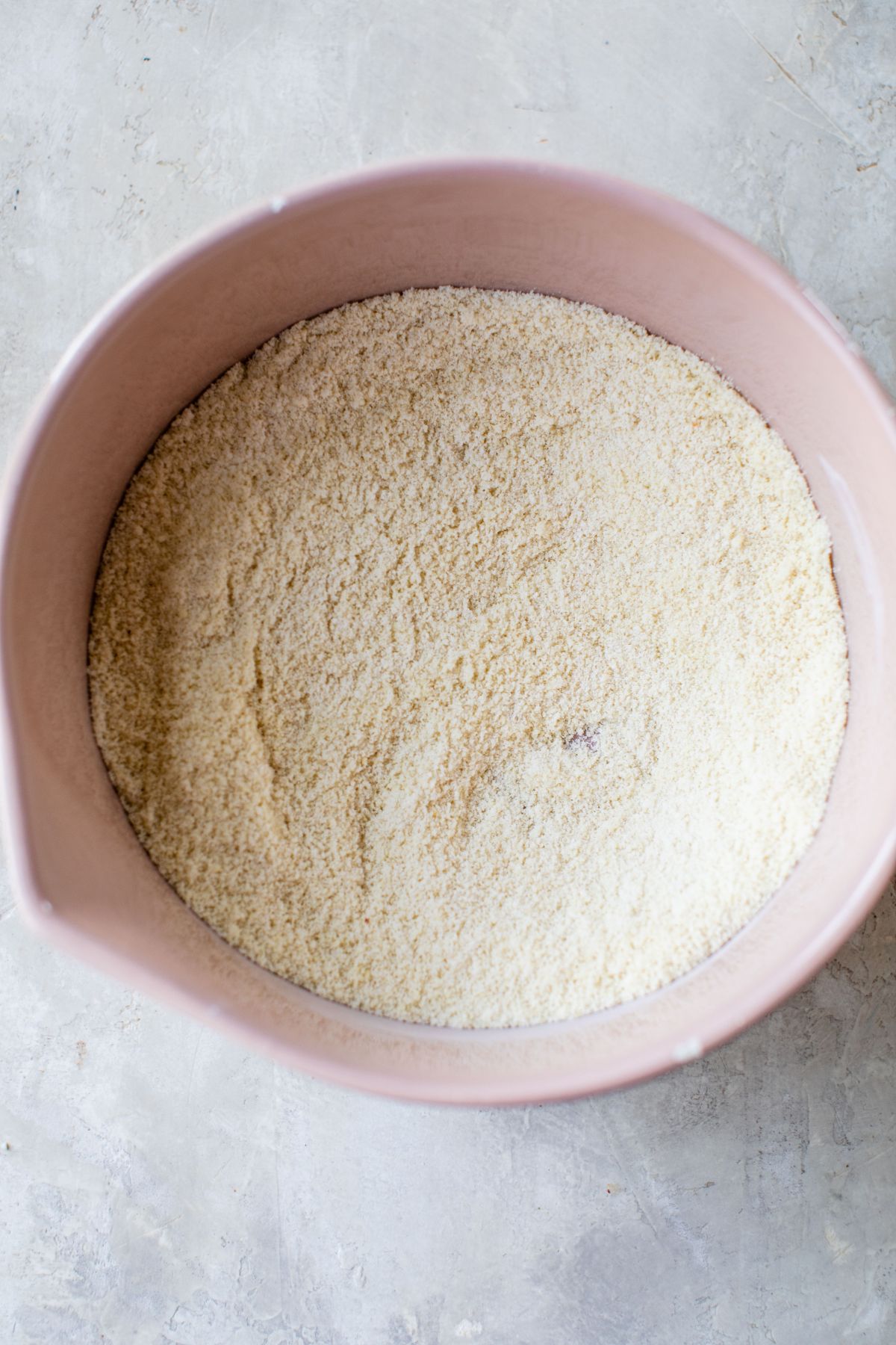 Combining almond flour with other dry ingredients in a large bowl.