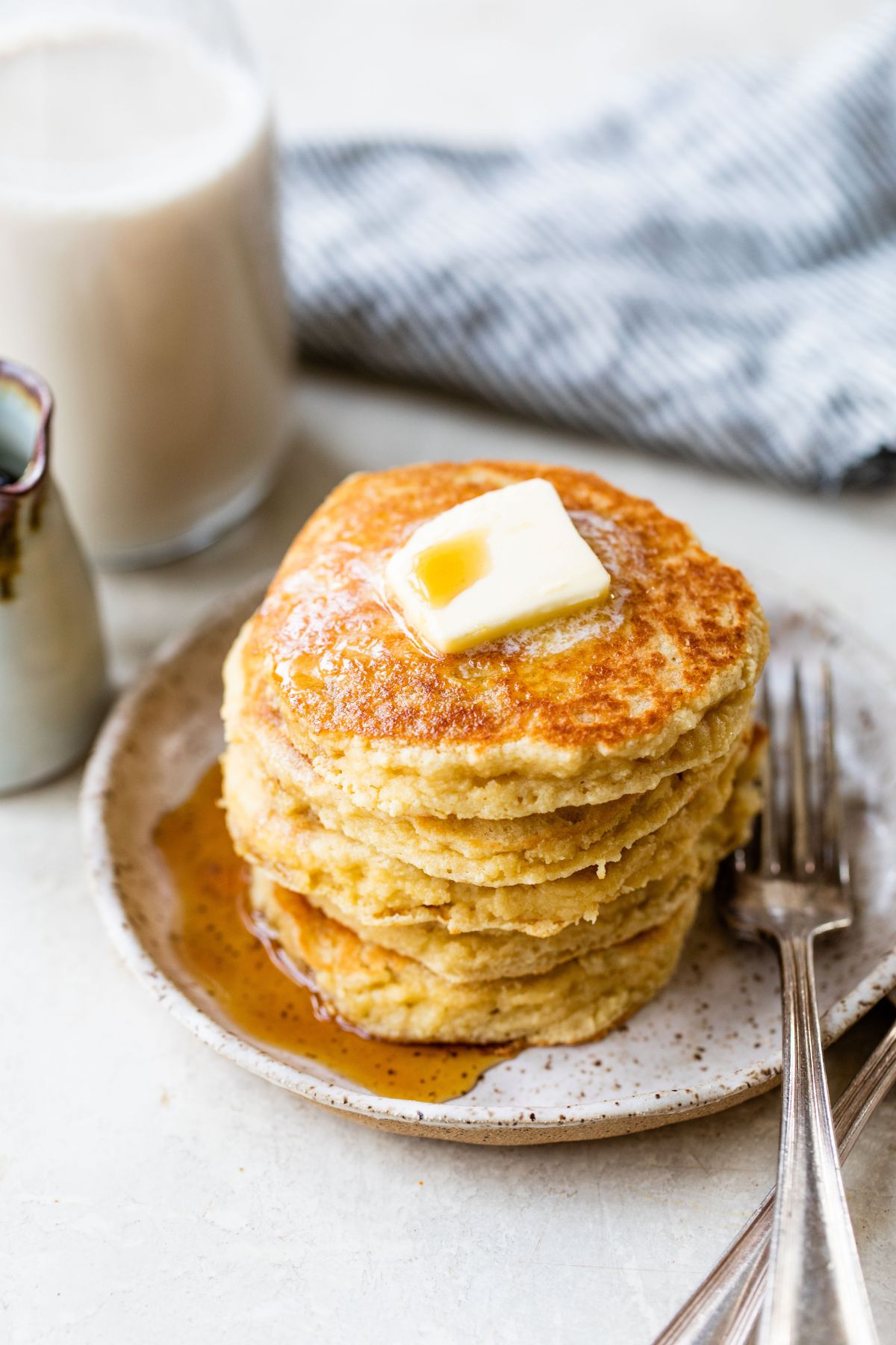 Stack of almond flour pancakes topped with a pat of butter and maple syrup.