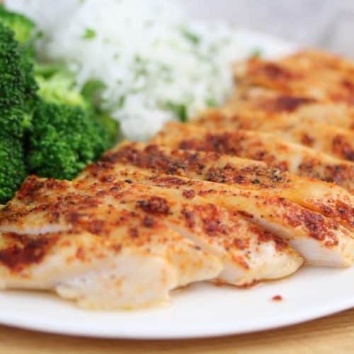 baked chicken breast on a white plate with jasmine rice and steamed broccoli