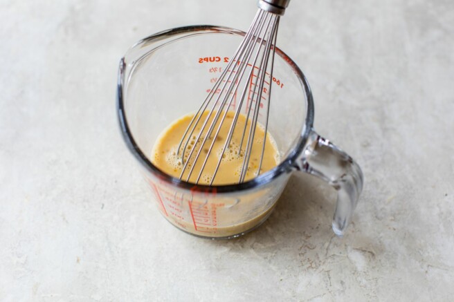 Whisking egg in milk in spouted measuring glass.