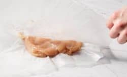 showing raw chicken breast on parchment paper