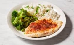 chicken breast served on a plate with broccoli and rice