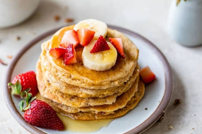 Stack of pancakes served with fresh fruit.